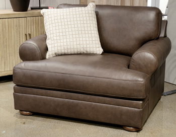 Brown leather chair with patterned throw pillow and ottoman-style base