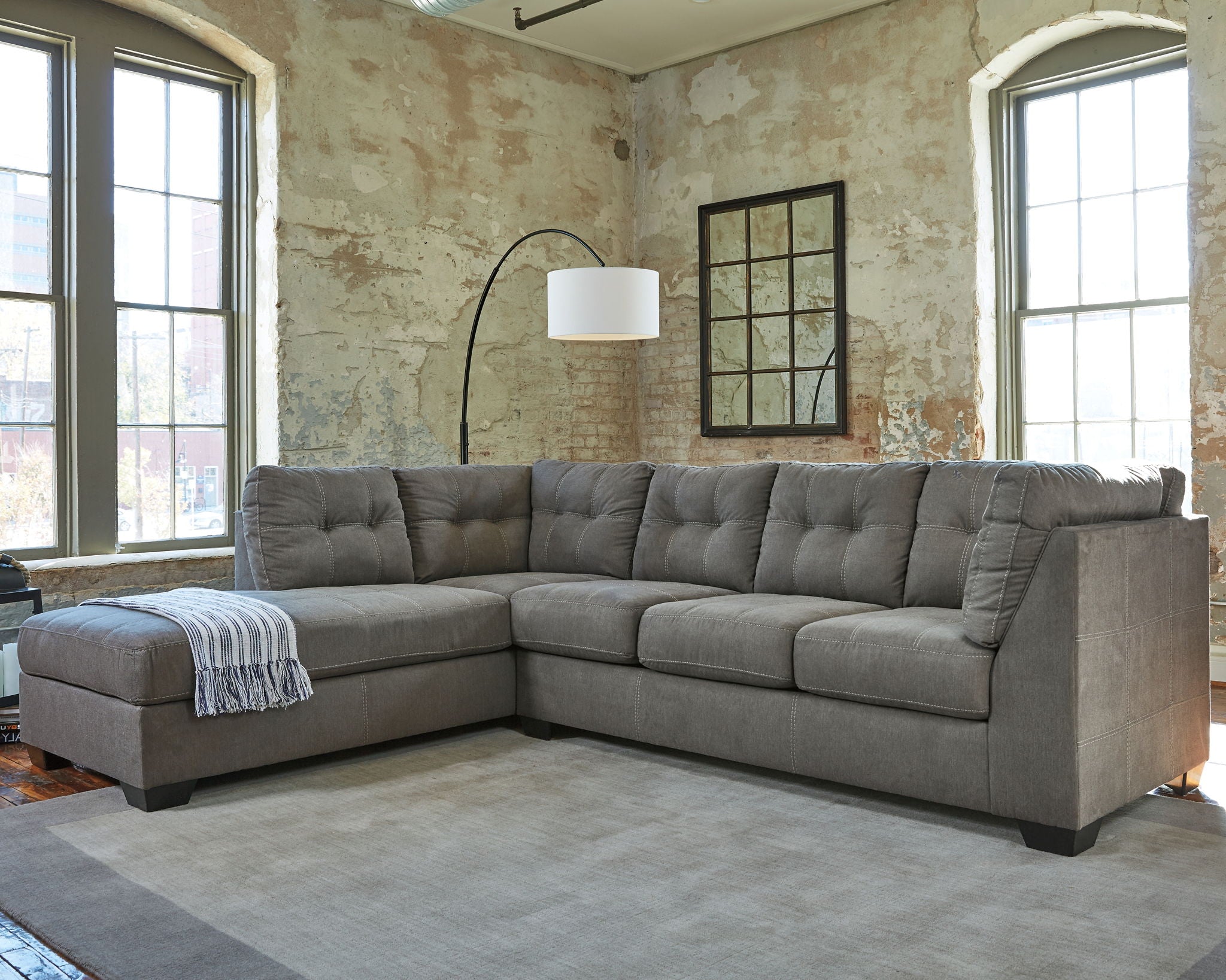 Slate gray sectional sofa with chaise, deep cushions and boxy tufted back.