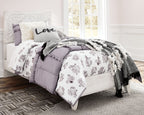 White panel bed with floral quilt, gray throw, and pillows including a 'Love' cushion