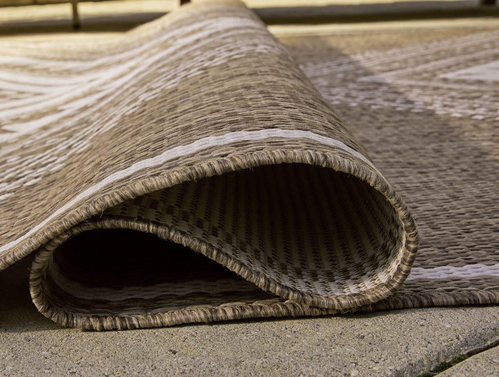 Rolled edge of brown rug with cream geometric stripes and frayed fringe