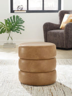 Light brown swivel accent ottoman with round padded top on a stacked upholstered base.