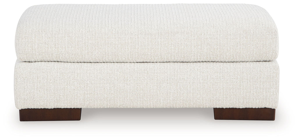 Cream upholstered ottoman with rounded top and dark wooden feet, low profile