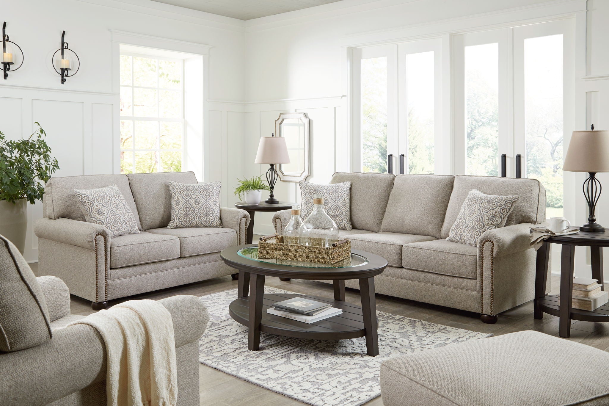 Light gray sofa set with multiple cushions and patterned pillows in a living room.