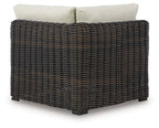 Corner sofa chair with beige back cushions on dark brown wicker