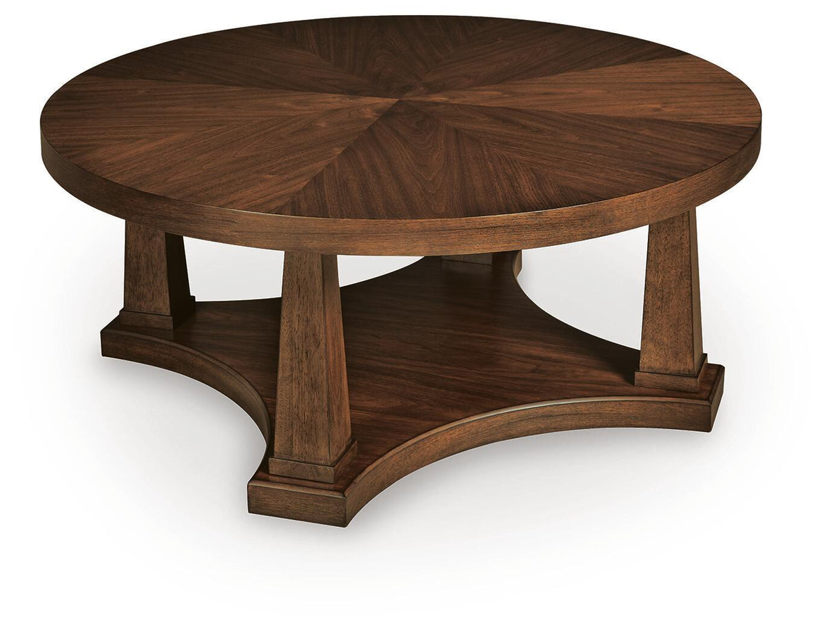 Round wooden coffee table with light brown top and pedestal base, angled view