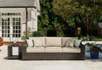 Brown wicker outdoor sofa with beige cushions and two patterned throw pillows