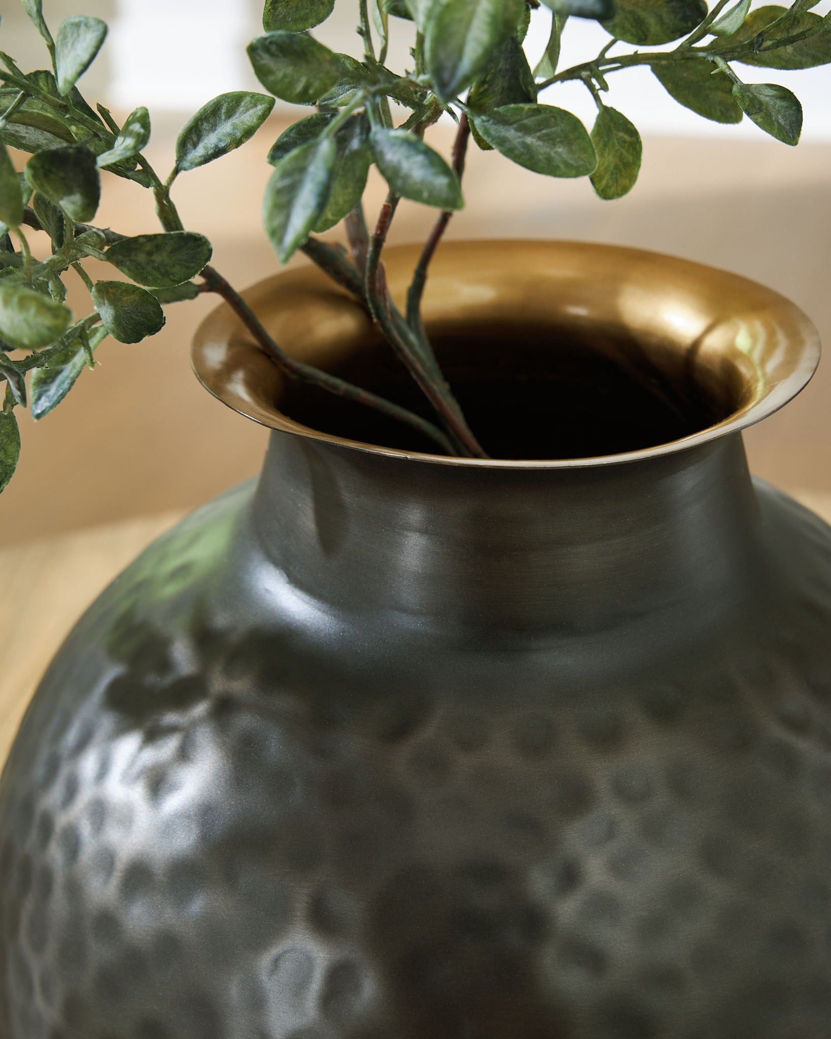 Dark gray hammered ceramic vase neck with gold-toned opening and leaf stems