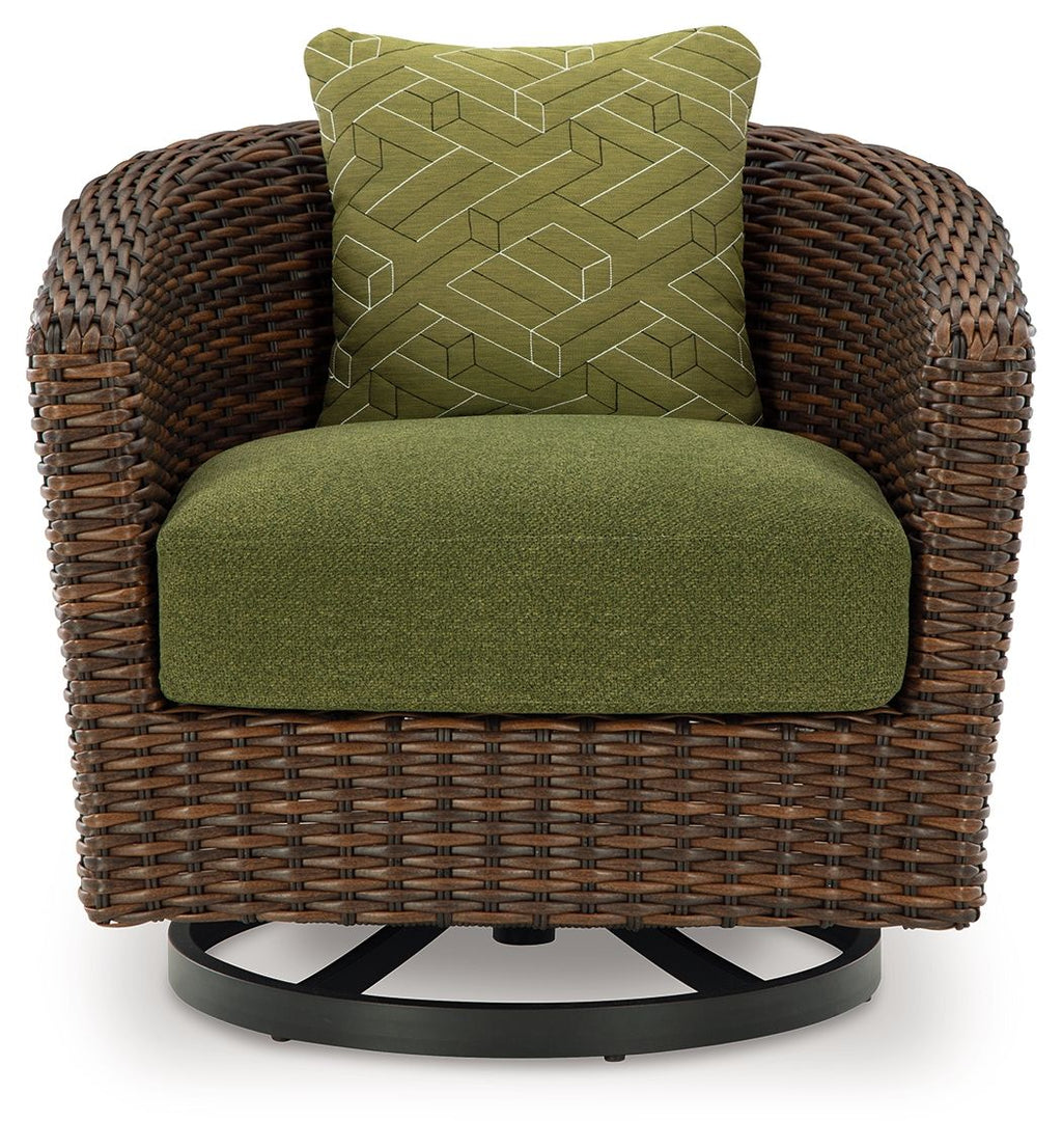 Brown woven swivel lounge chair with green seat cushion and patterned green back pillow