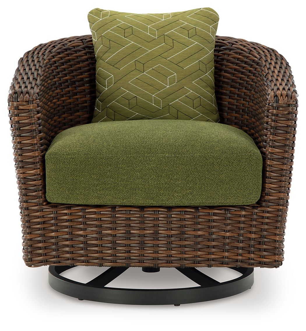 Brown woven swivel lounge chair with green seat cushion and patterned green back pillow