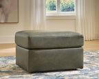 Olive ottoman with padded top and visible stitching; short black feet.