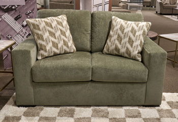 Green upholstered loveseat with two geometric throw pillows