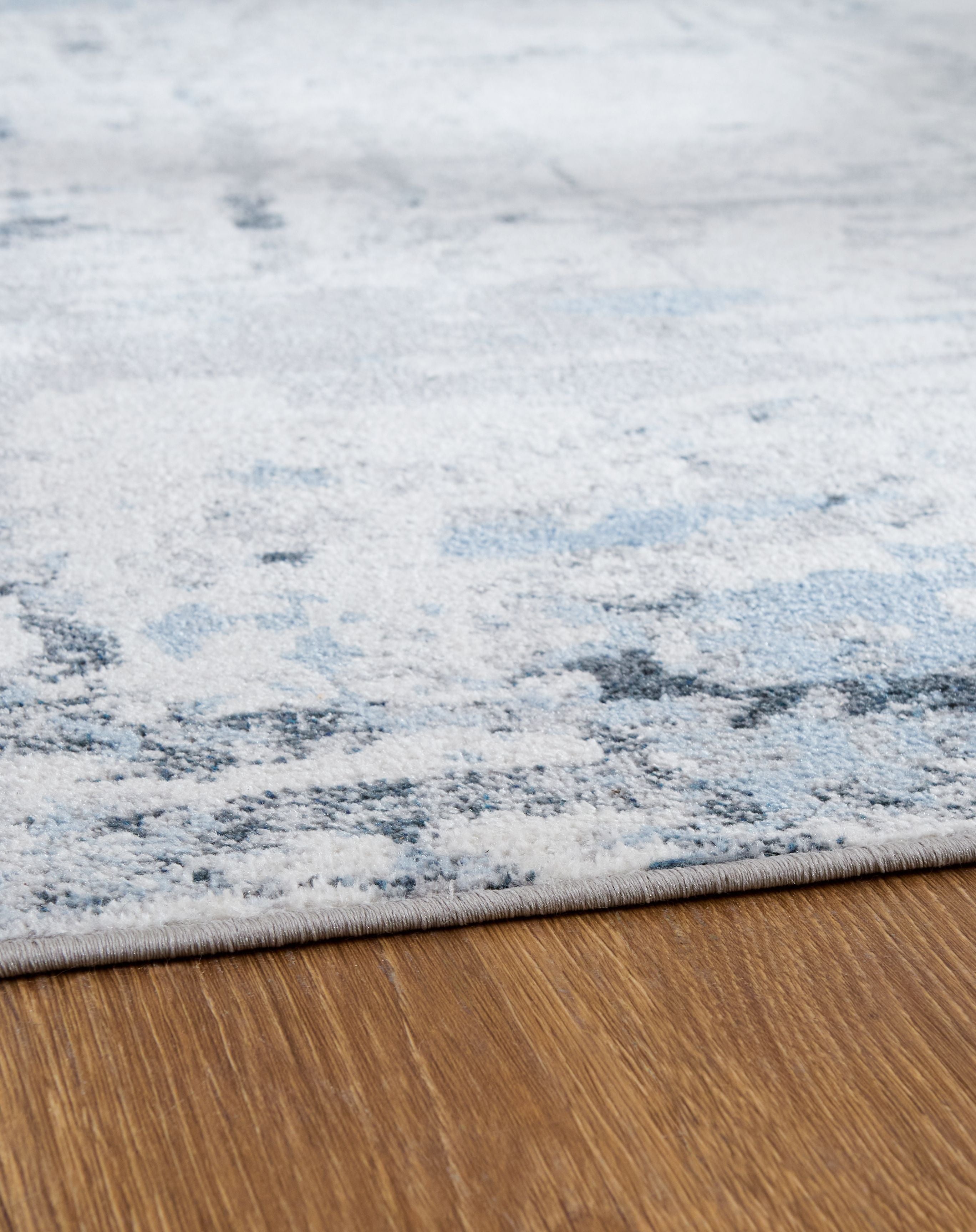 Light blue washable rug with faded abstract bands and mottled low-pile texture