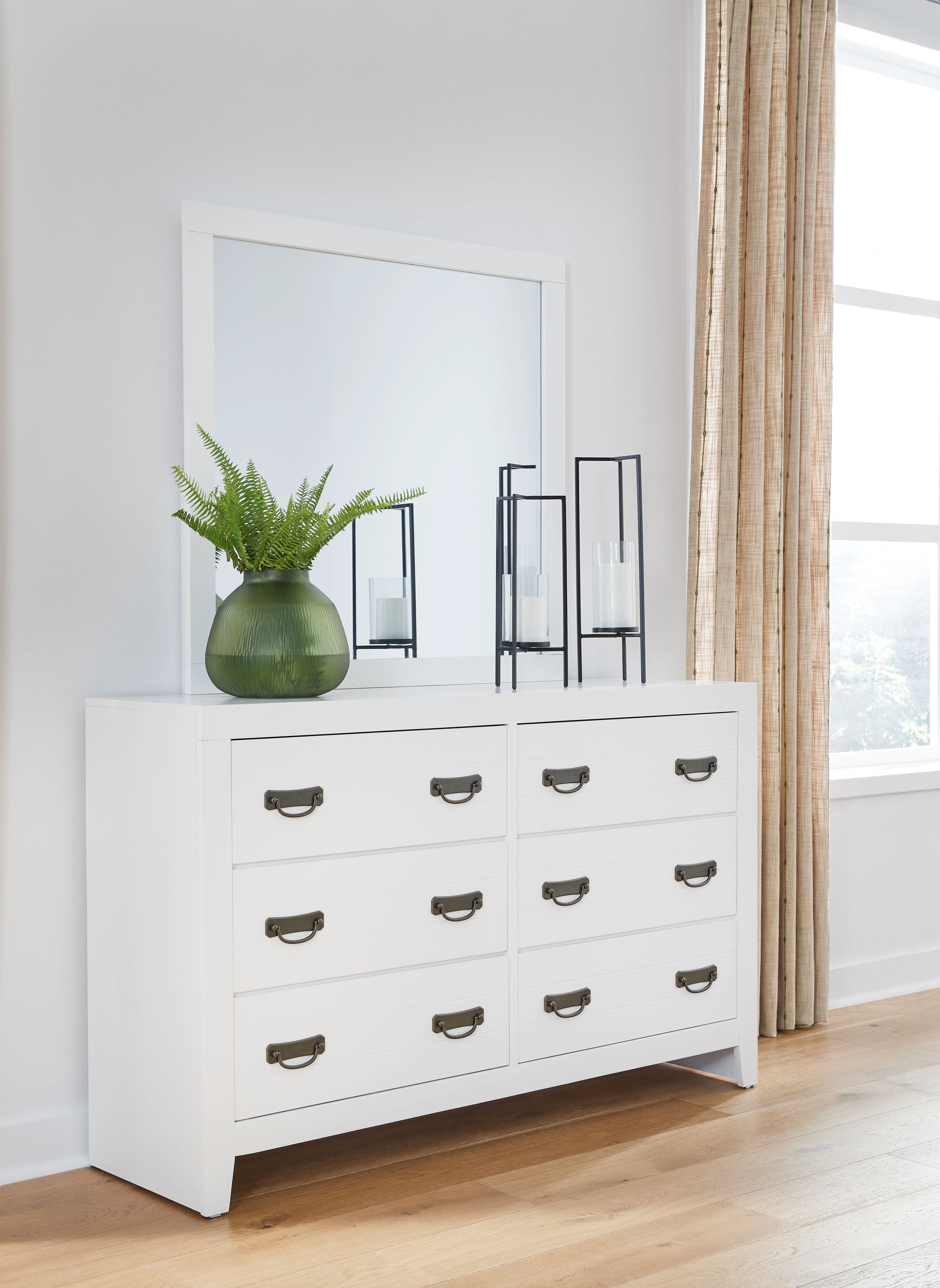White dresser with attached mirror and six drawers with bronze cup handles