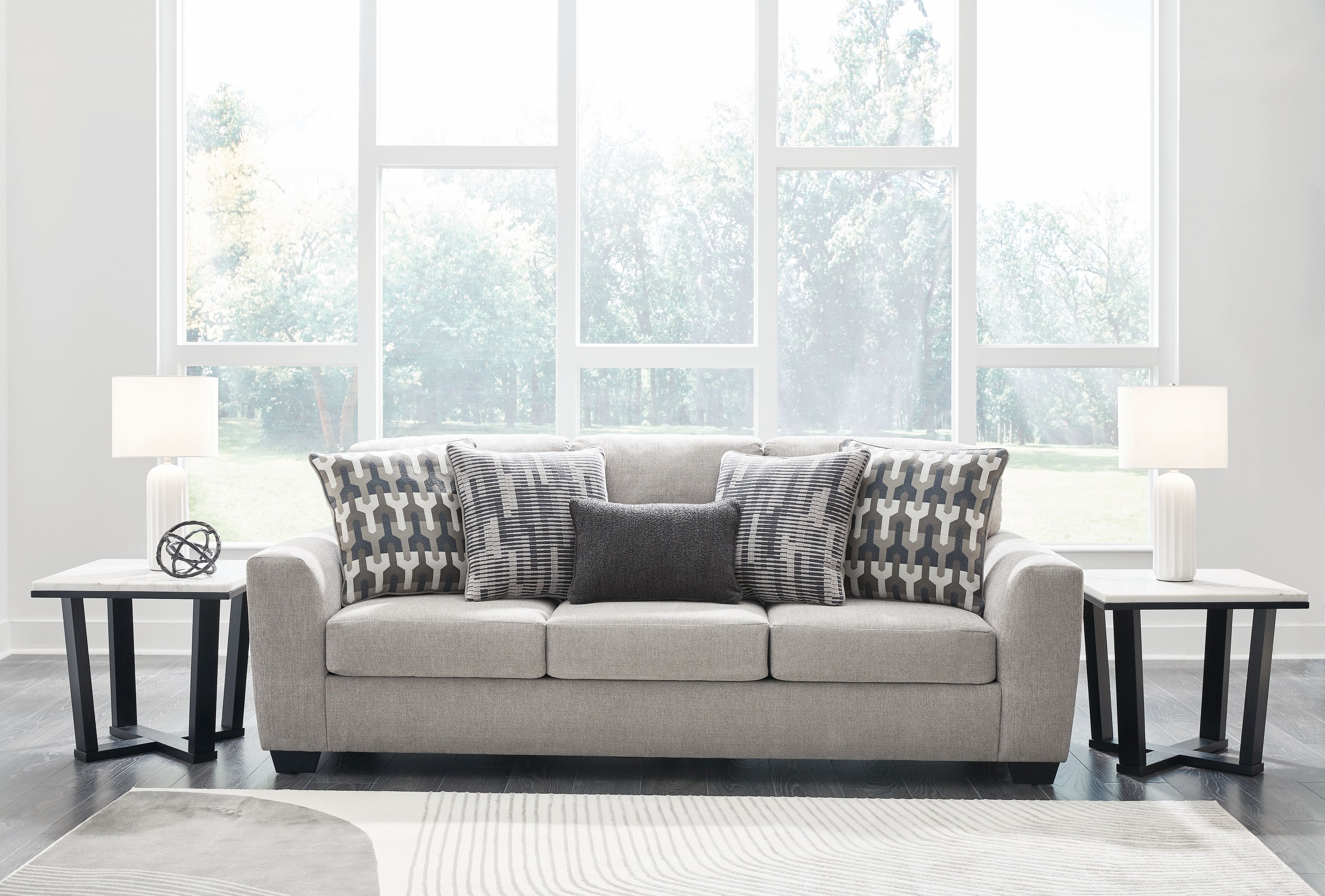 Gray flannel sofa with three-seat layout, patterned pillows, and dark legs