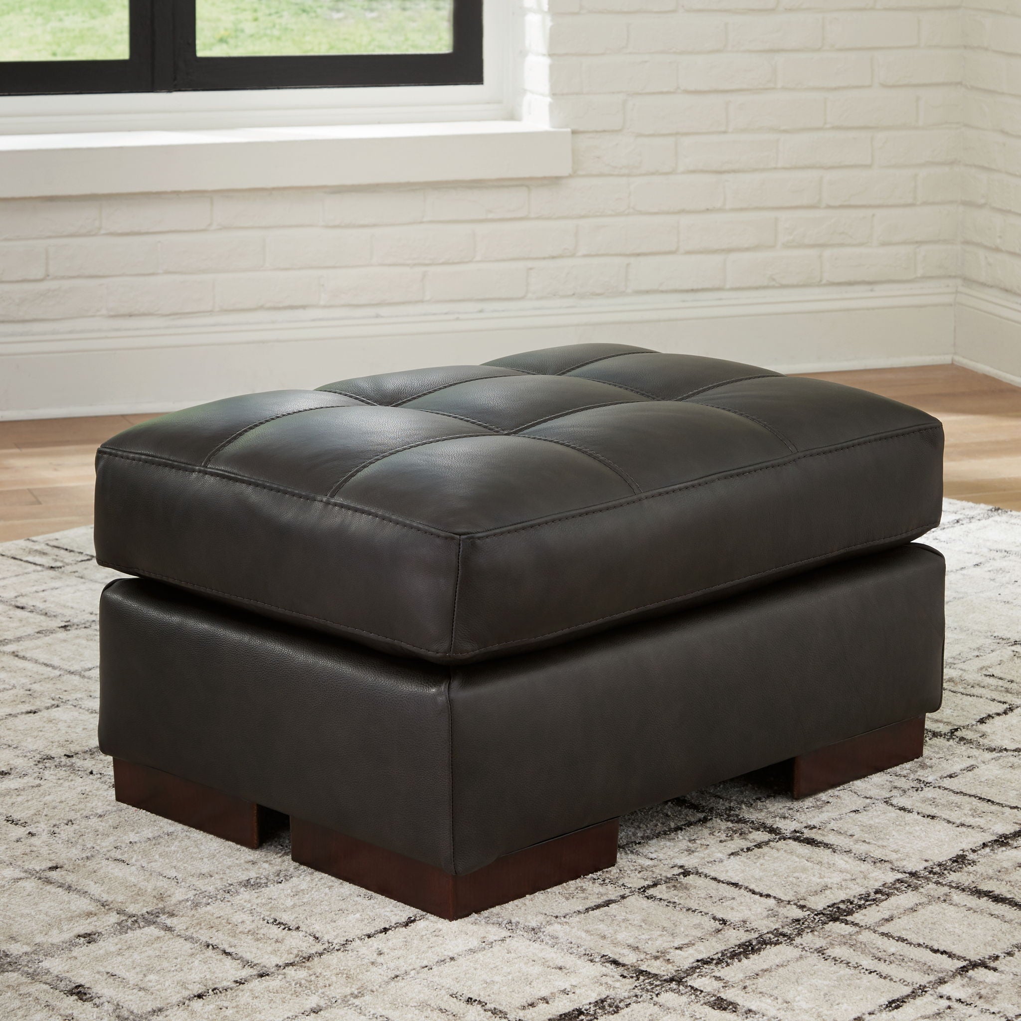Dark brown upholstered ottoman with tufted lid, square base, dark wooden block feet