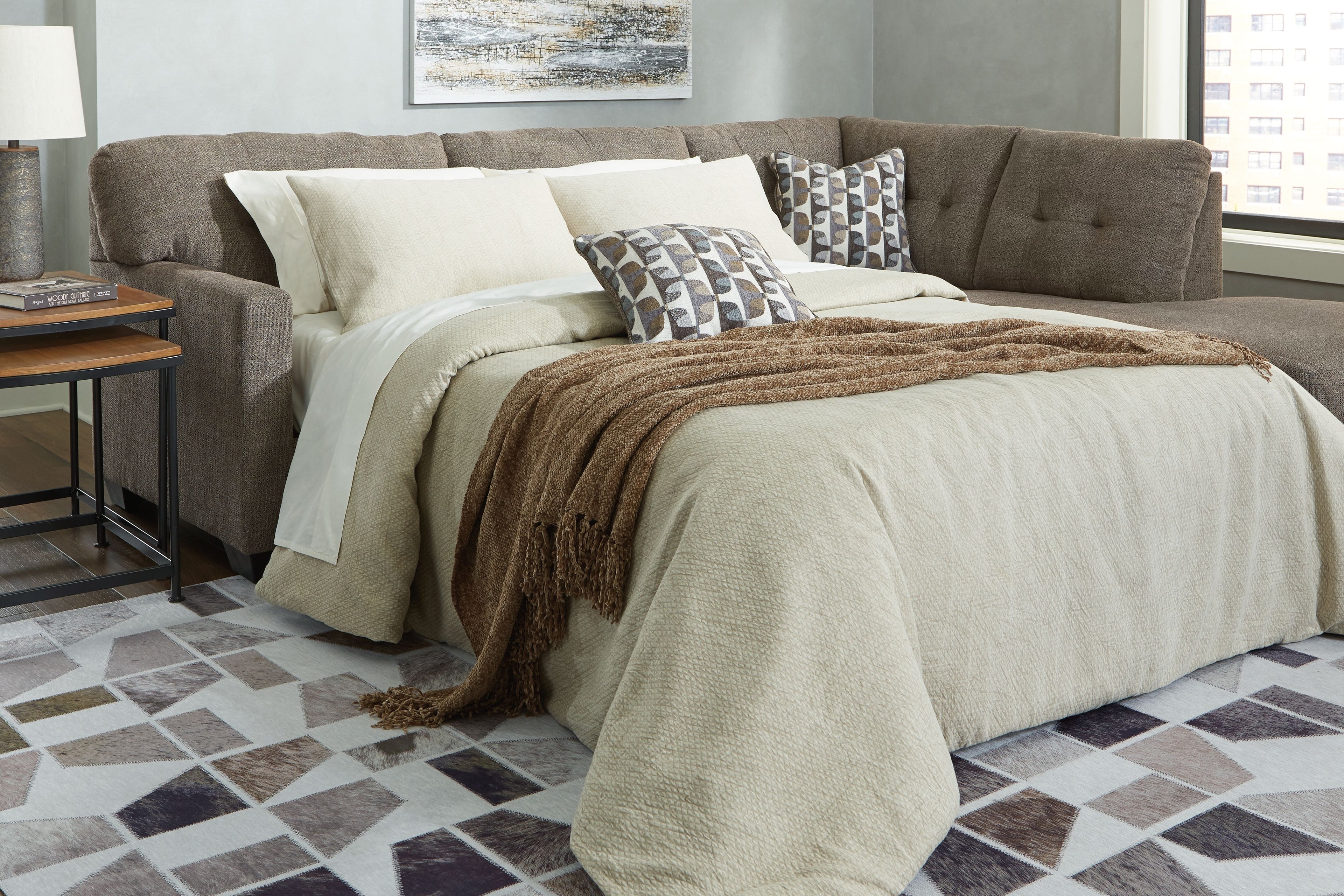 Chocolate-brown full sofa sleeper with bed unfolded and layered blankets