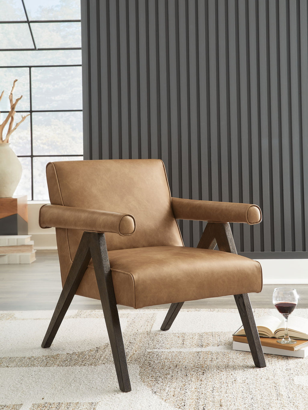Tan faux-leather accent chair with curved arms, tufted back detail, and dark legs