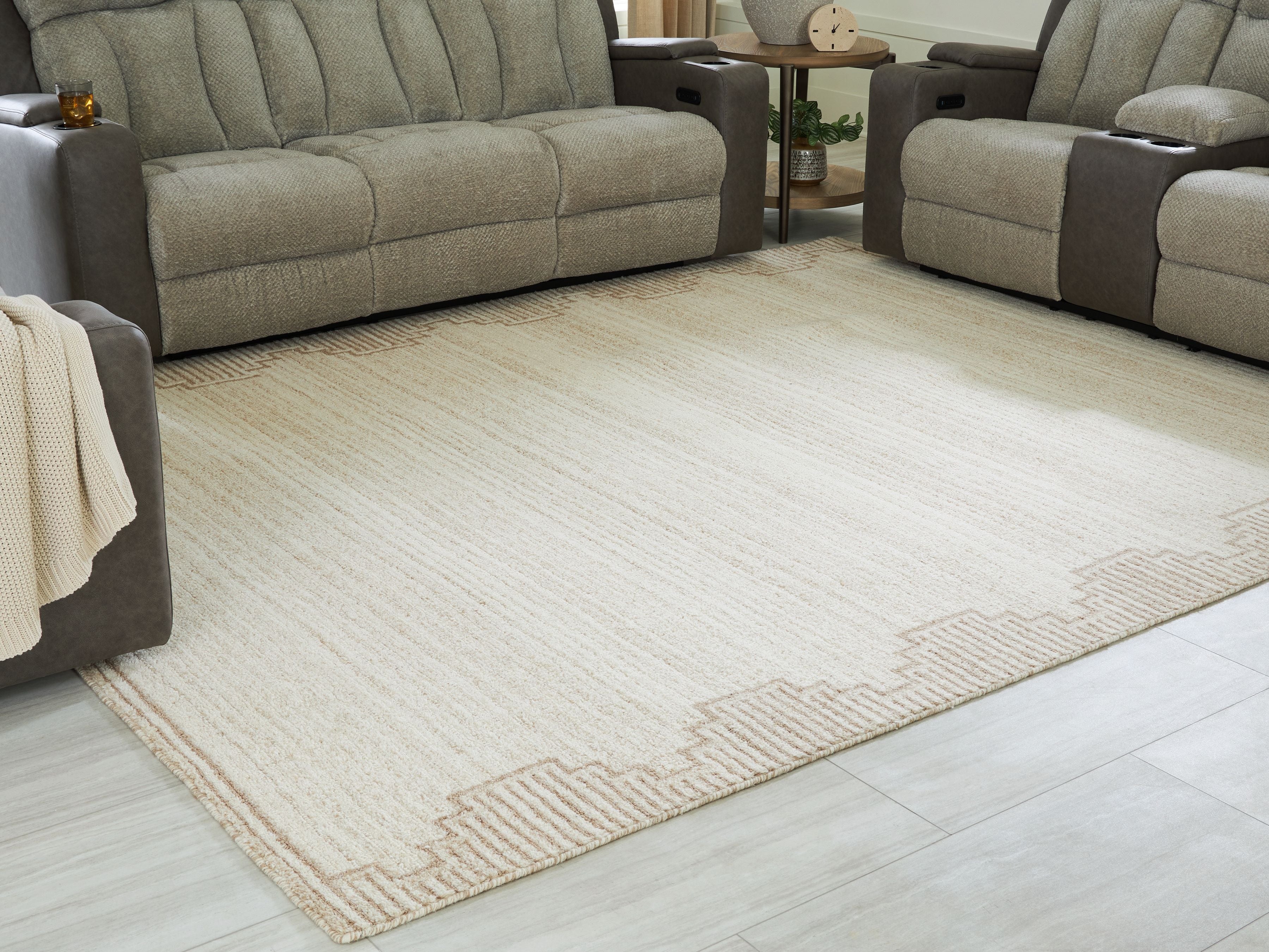 Beige rug featuring geometric corner pattern and low, textured pile