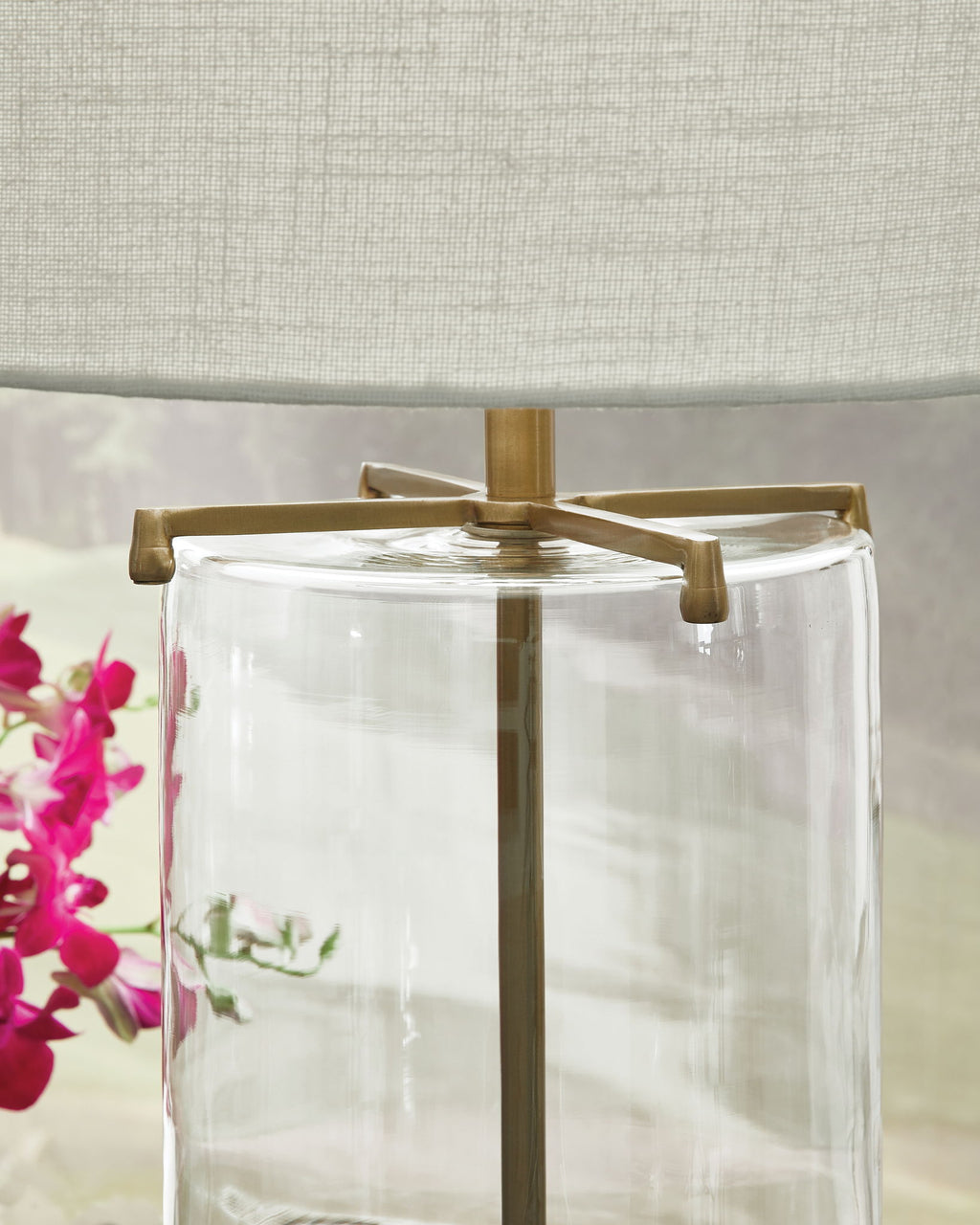 Clear glass lamp body with gold hardware and white fabric shade