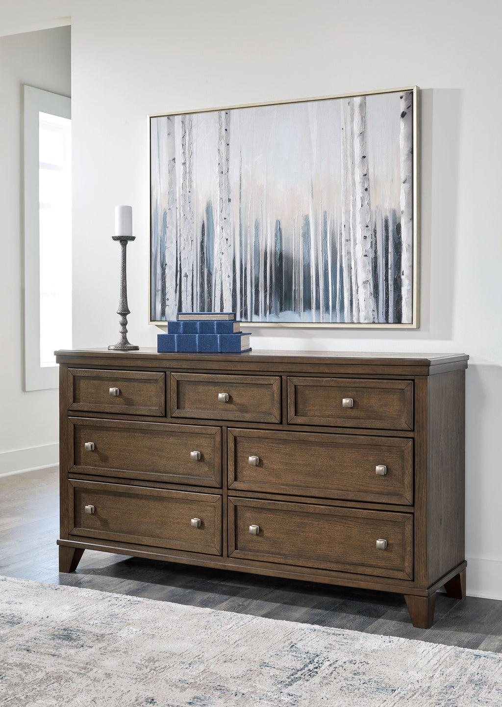 Medium brown wood dresser with multiple drawers and silver knobs, shown in living space