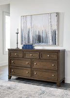 Medium brown wood dresser with multiple drawers and silver knobs, shown in living space