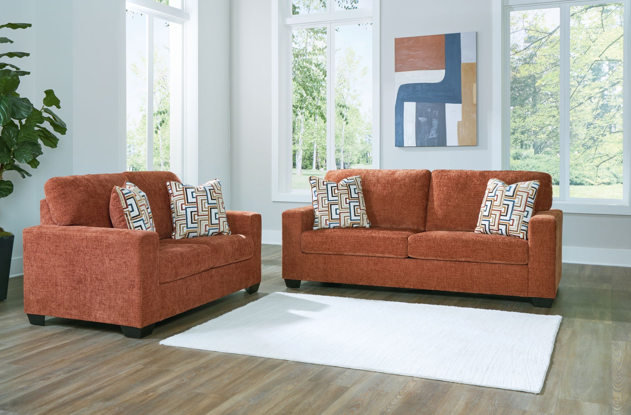 Terracotta loveseat and sofa with patterned pillows