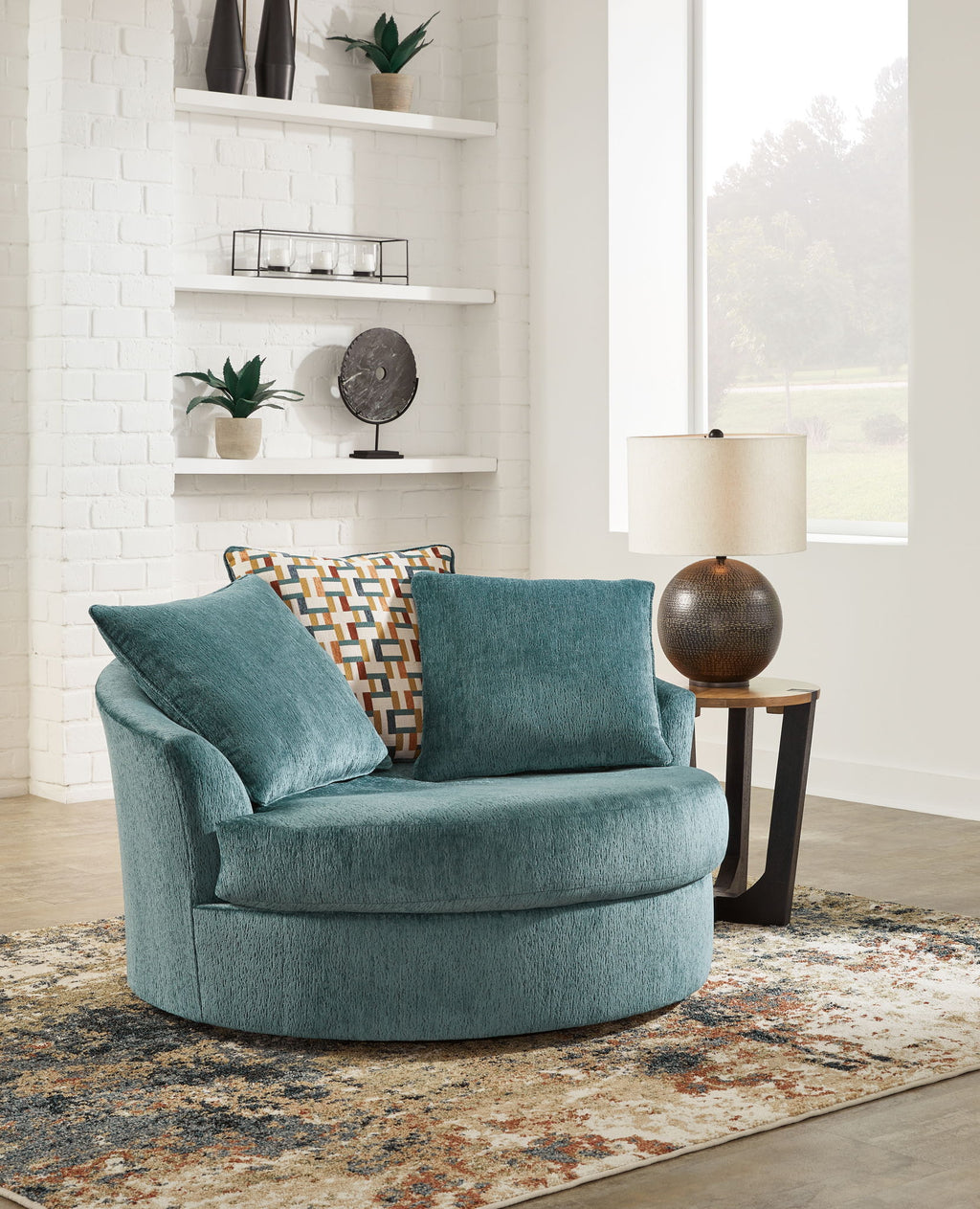 Teal oversized swivel accent chair with patterned lumbar pillow and two cushions