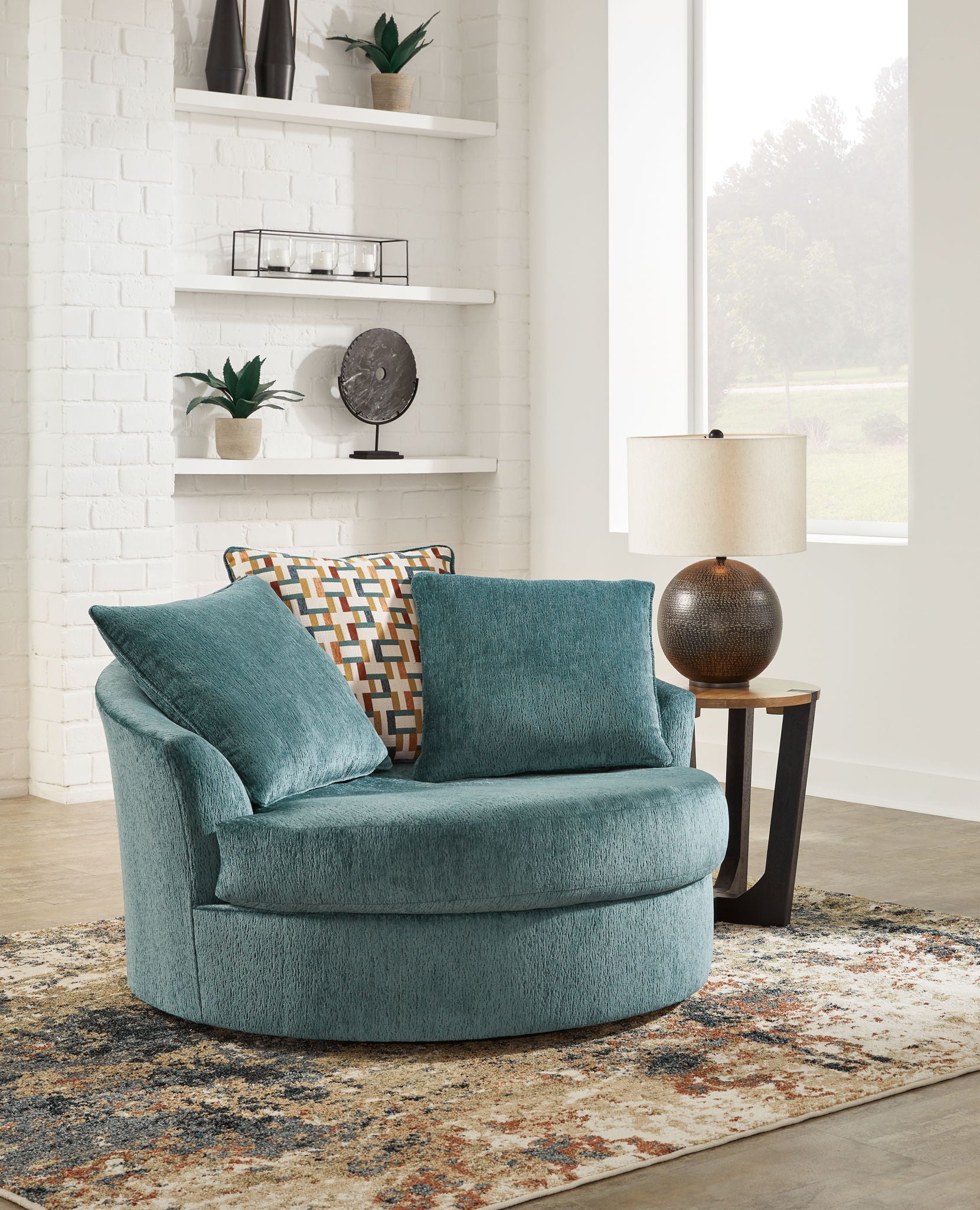 Teal oversized swivel accent chair with patterned lumbar pillow and two cushions