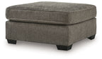 Dark gray ottoman with padded lid, rounded edges, and dark block legs