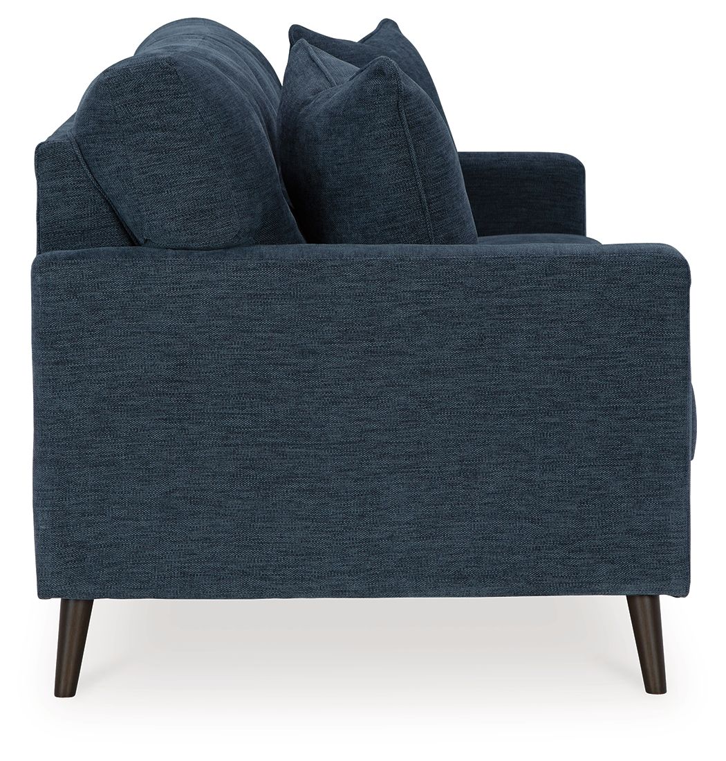 Blue upholstered sofa viewed from the side with four throw pillows