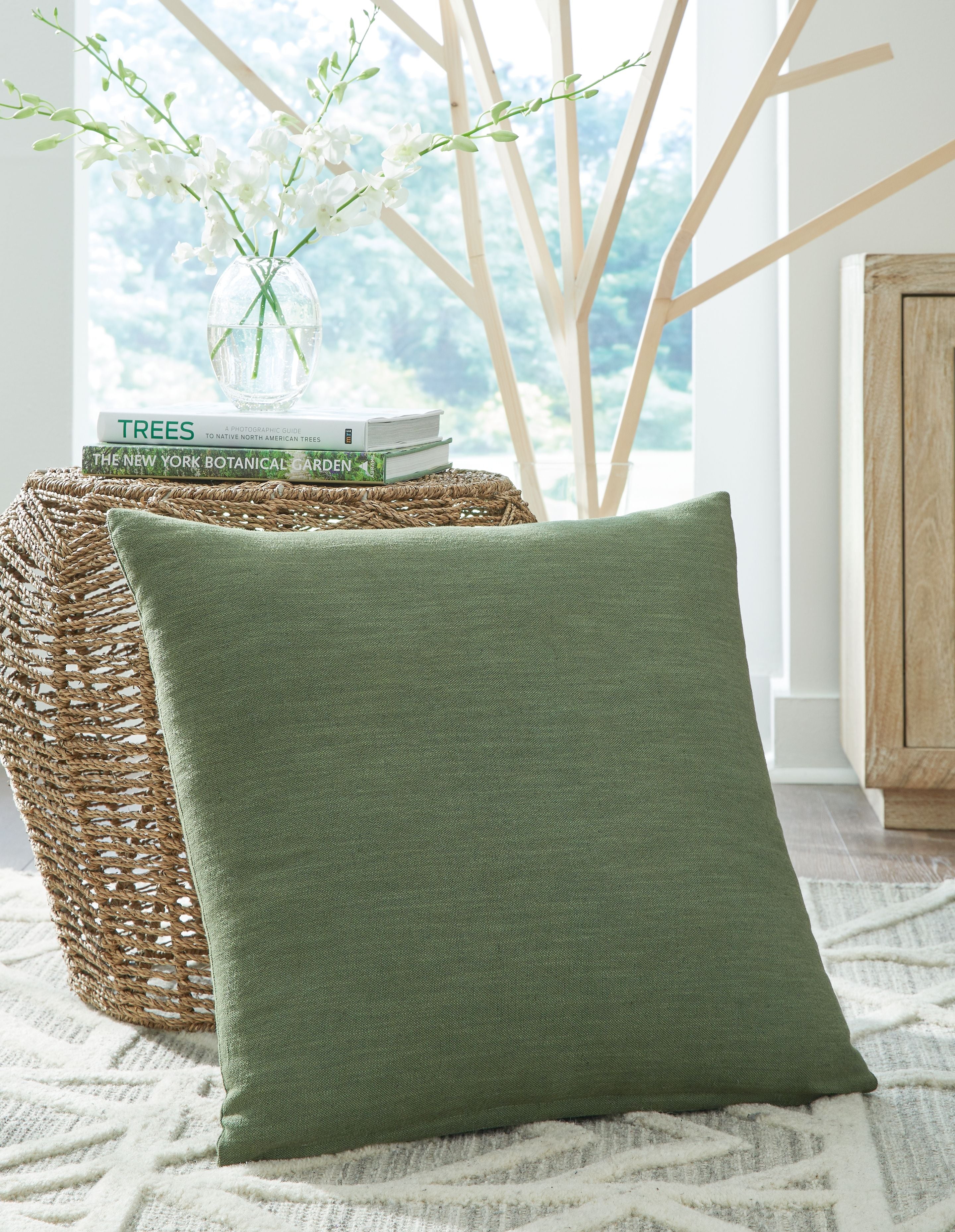 Green square throw pillow with plain woven fabric and visible stitched seams