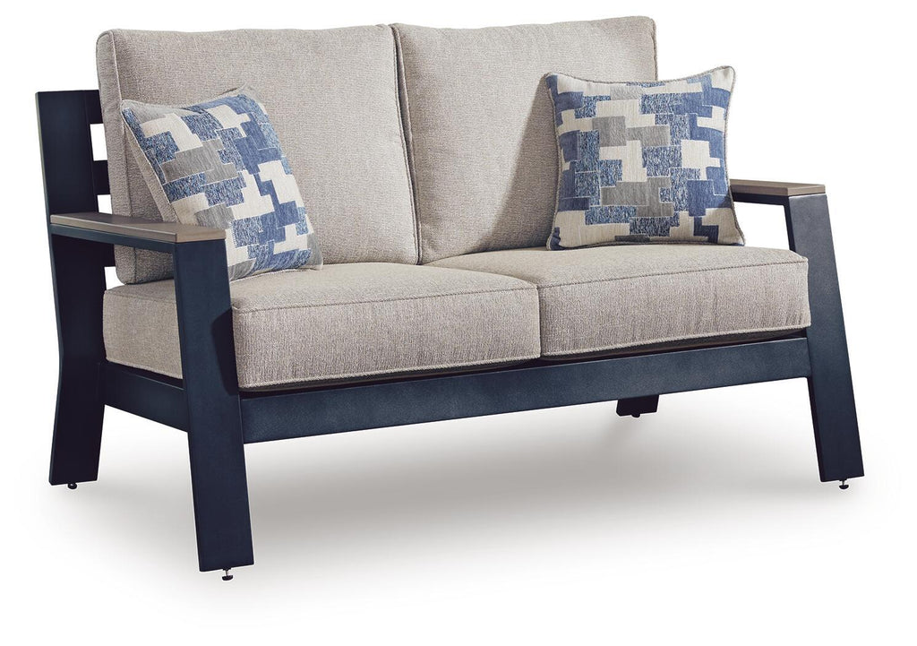 Blue patterned throw cushions on gray loveseat with armrests and two-seat cushion