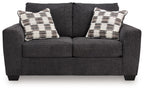 Dark gray loveseat with two plaid throw pillows and tufted seat back
