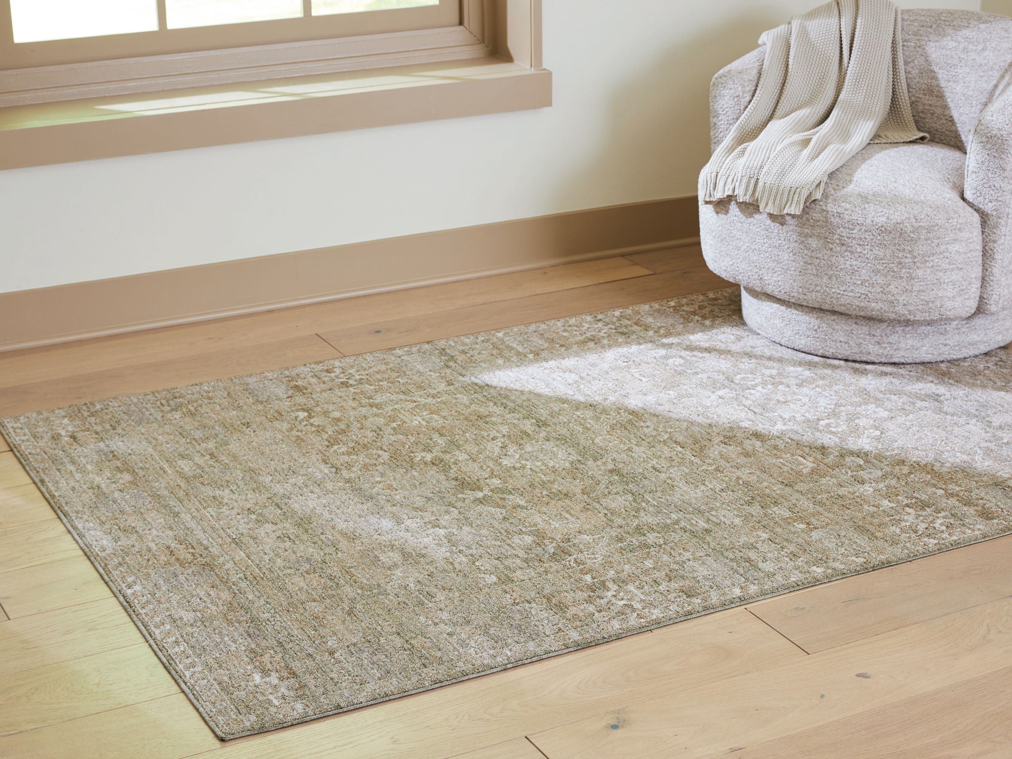 Light brown flatweave area rug laid on hardwood, muted distressed pattern