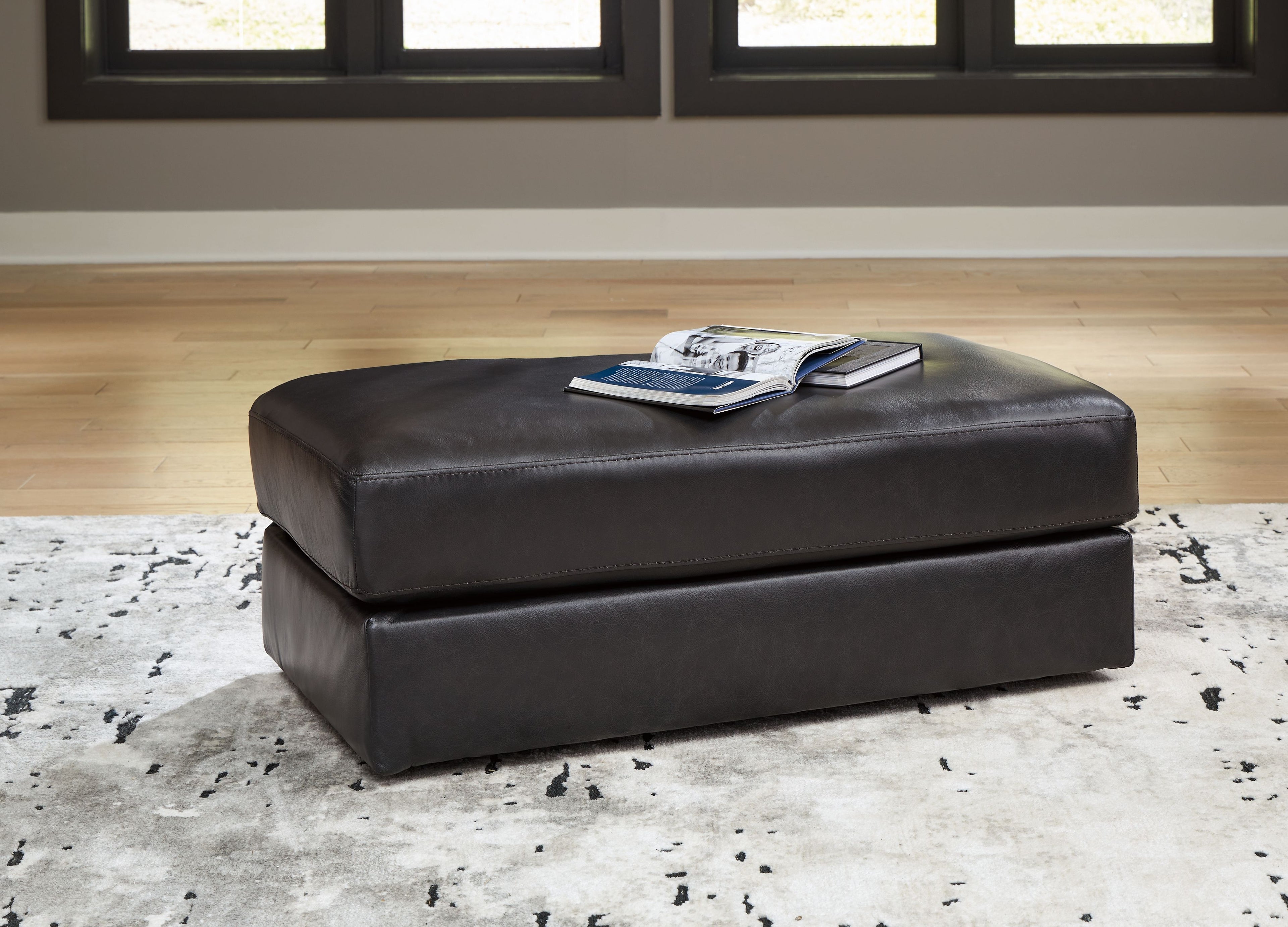 Onyx leather ottoman with padded top and square base on short legs