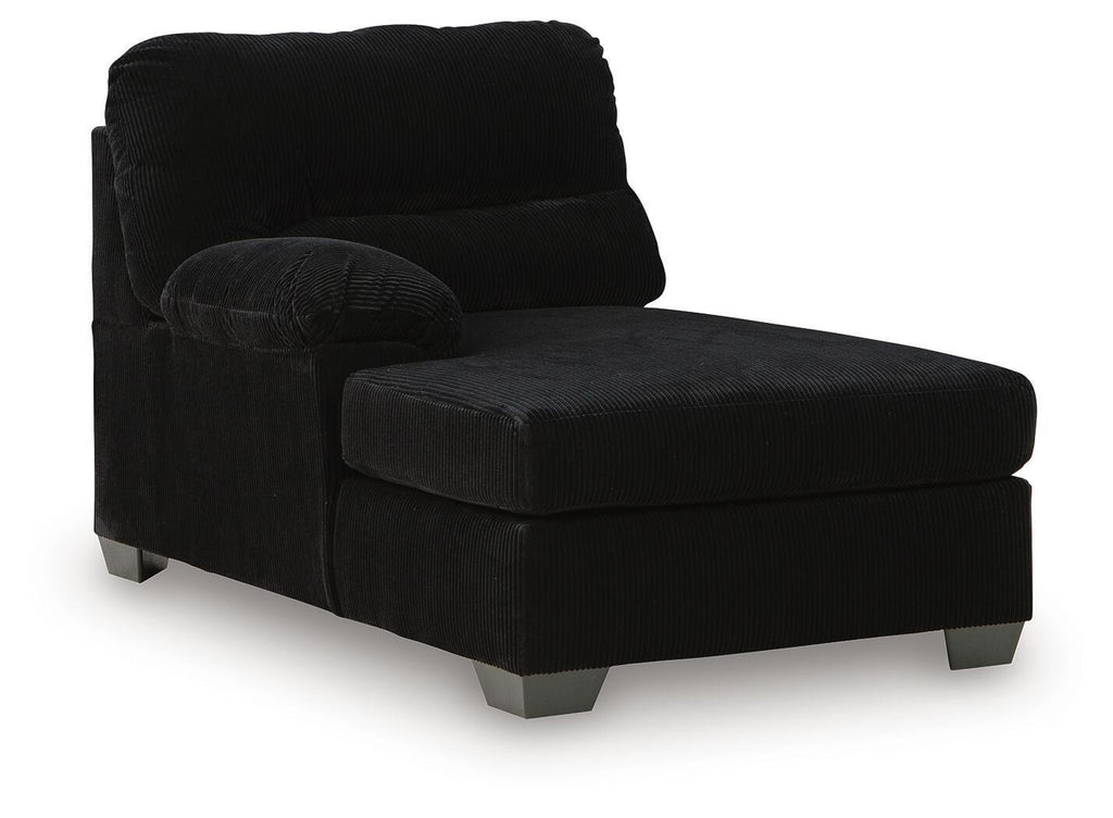 Corner chaise with dark corduroy upholstery, cushioned back, and ottoman-style seat