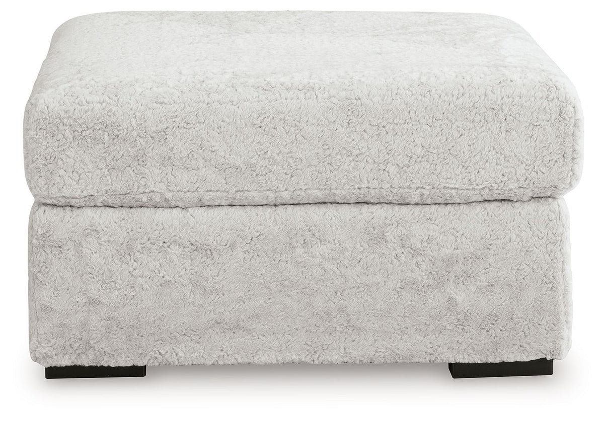 Plush ottoman with rounded top and textured light gray fabric, black feet