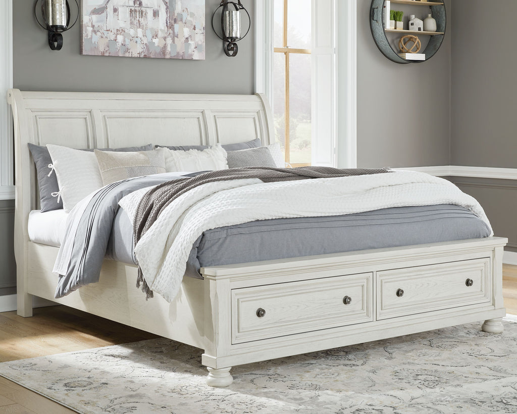 White sleigh bed with paneled headboard and footboard, styled with bedding and throw