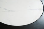 White marble-look tabletop close-up with light gray veining and black rim