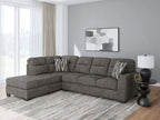 Dark gray sectional sofa with left chaise, tufted back, and striped pillows in a bright room
