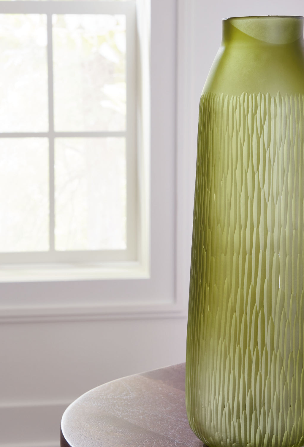 Green glass vase with tall narrow body, short neck, and vertical ridged texture.