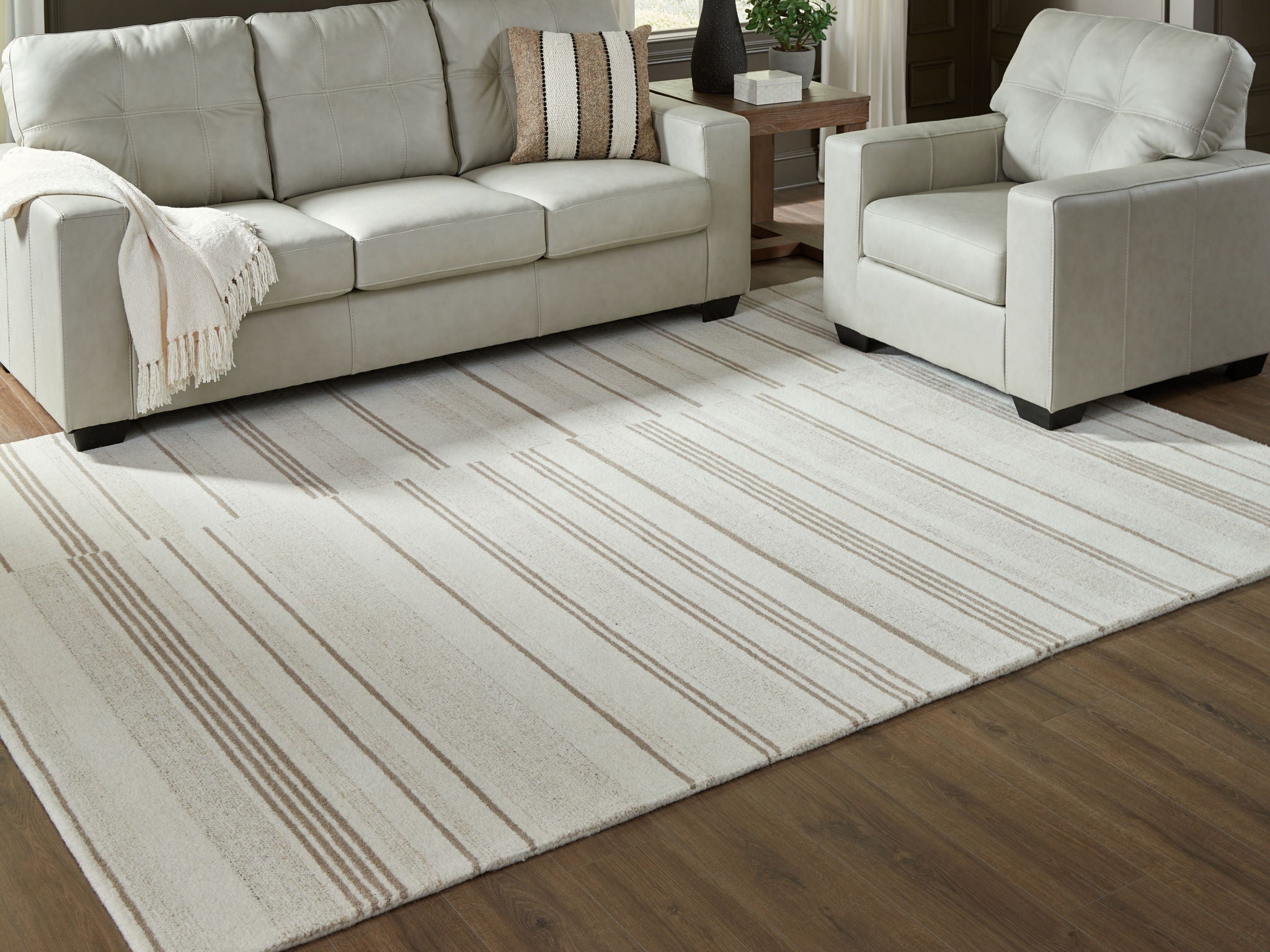 Rectangular off-white area rug with beige horizontal stripes under seating