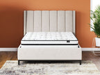 White hybrid mattress on dark platform bed with tufted headboard behind