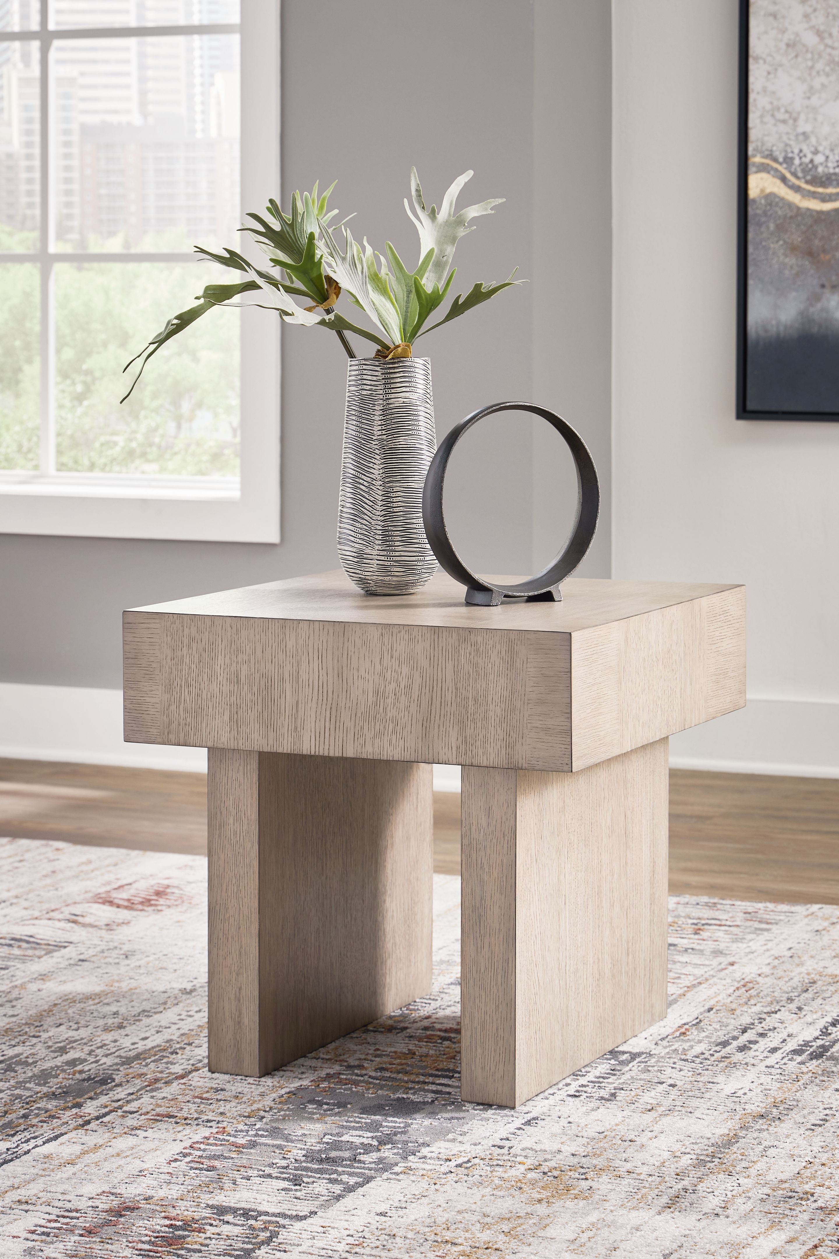 Square end table in light grayish brown with vase and mirror on top.