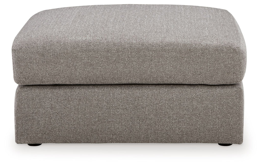 Smoke gray ottoman with rounded cushioned seat and low profile