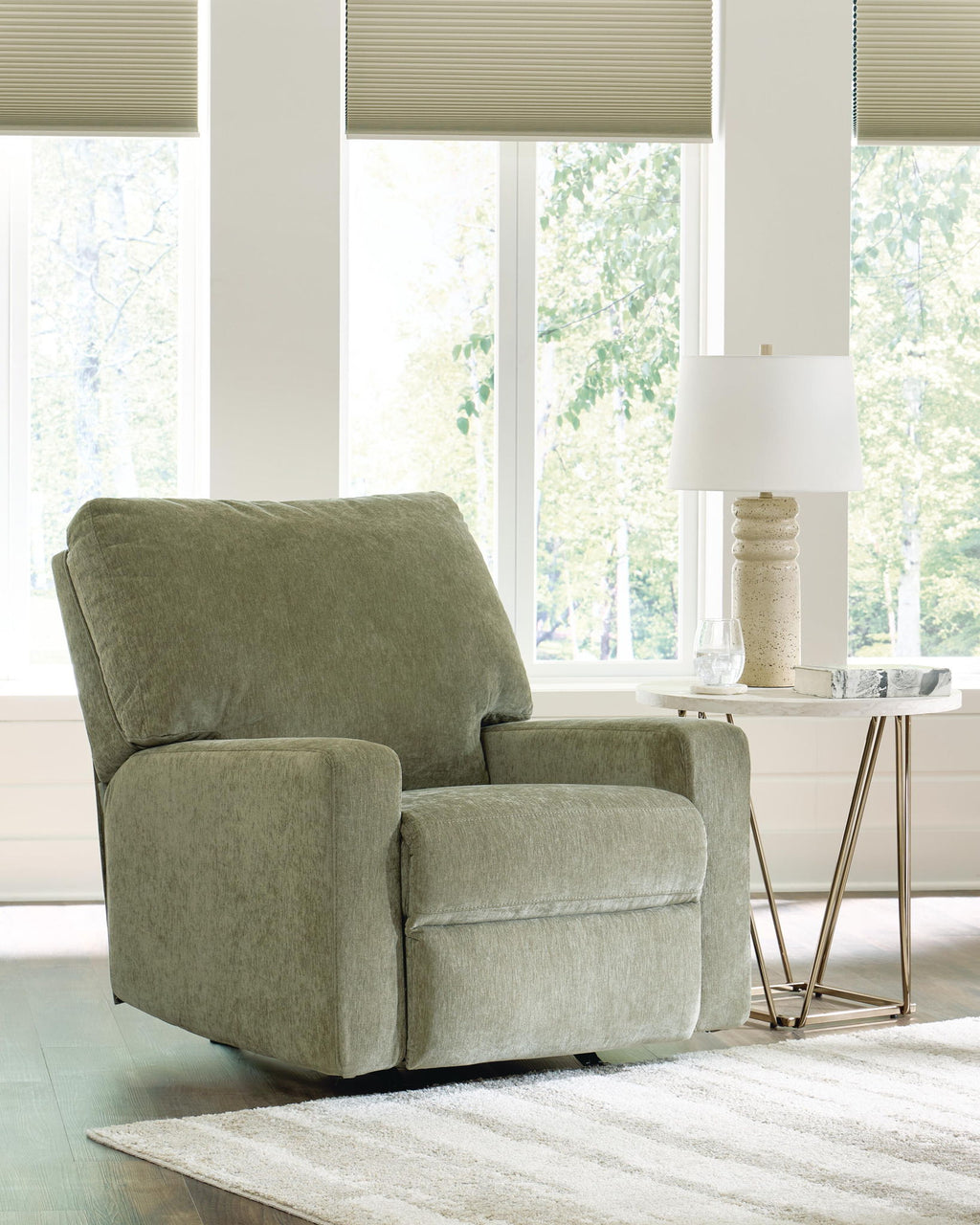 Green fabric rocker recliner chair with tall backrest and padded side arms.
