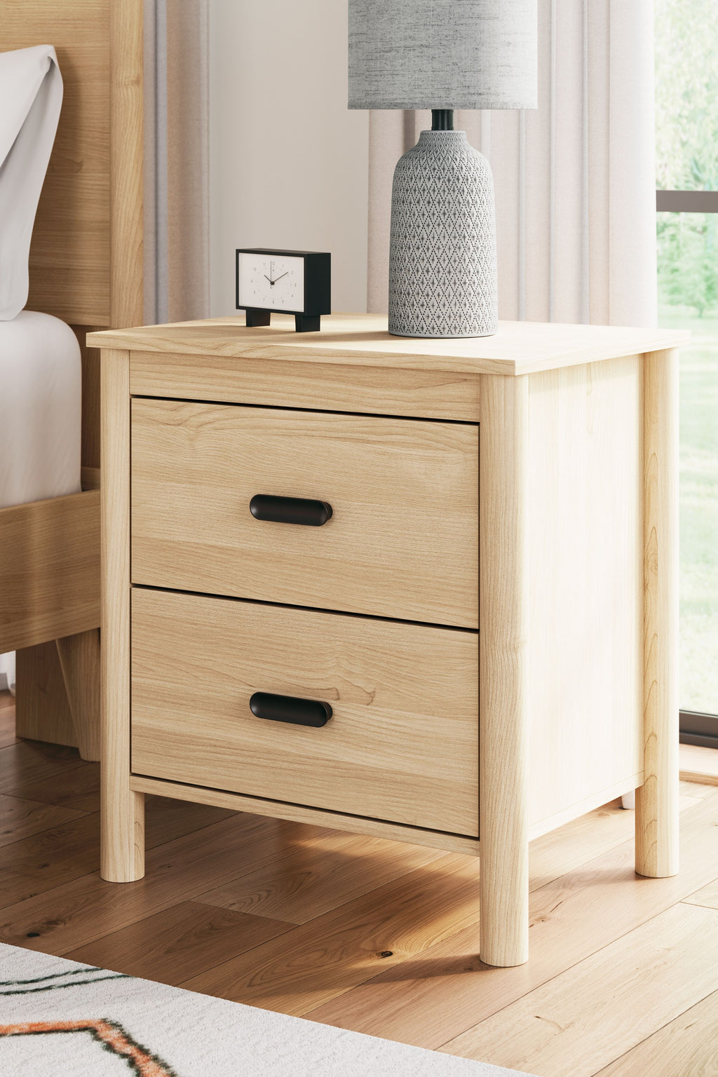 Light tan wood two-drawer nightstand with black pulls and tapered legs