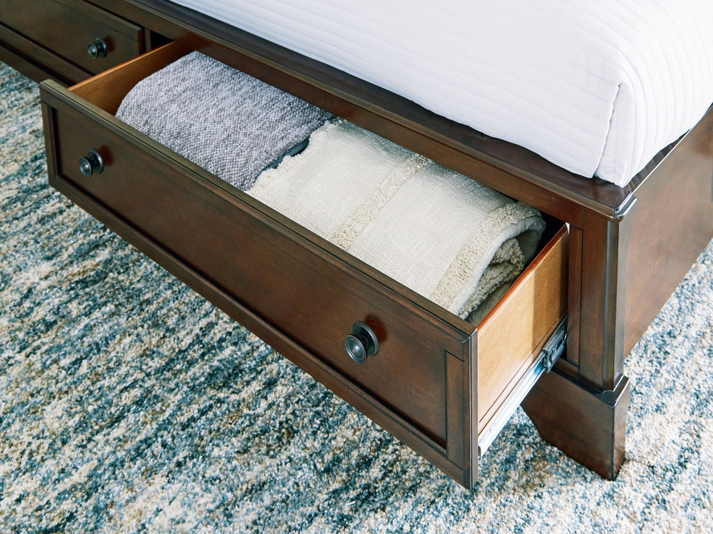 Brown storage bed drawer open on side, showing folded bedding inside