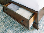 Brown storage bed drawer open on side, showing folded bedding inside