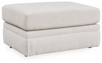 Light beige fabric ottoman with cushioned top, smooth sides, short dark legs